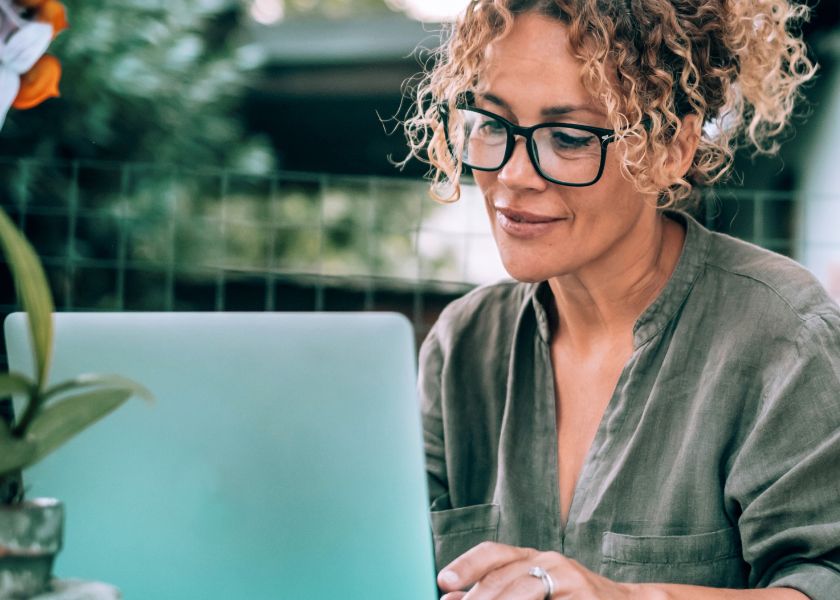 A focused woman with glasses works on her laptop, supporting her brain health and mental clarity with E3Live.