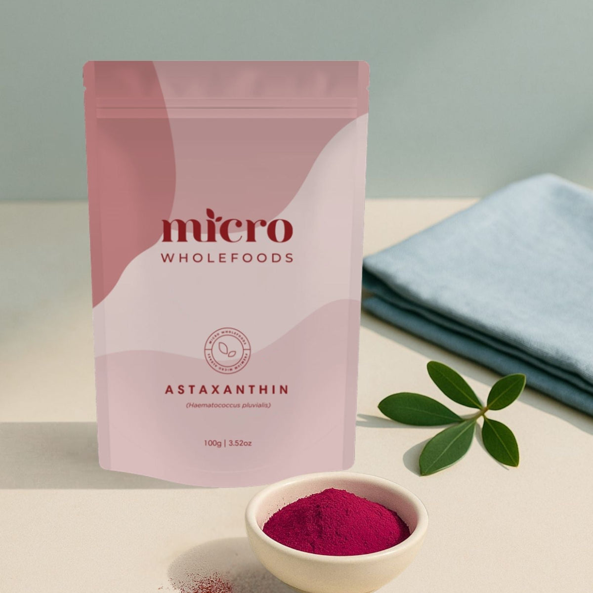 Pink package of micro wholefoods Astaxanthin with a bowl of powder on a light surface.