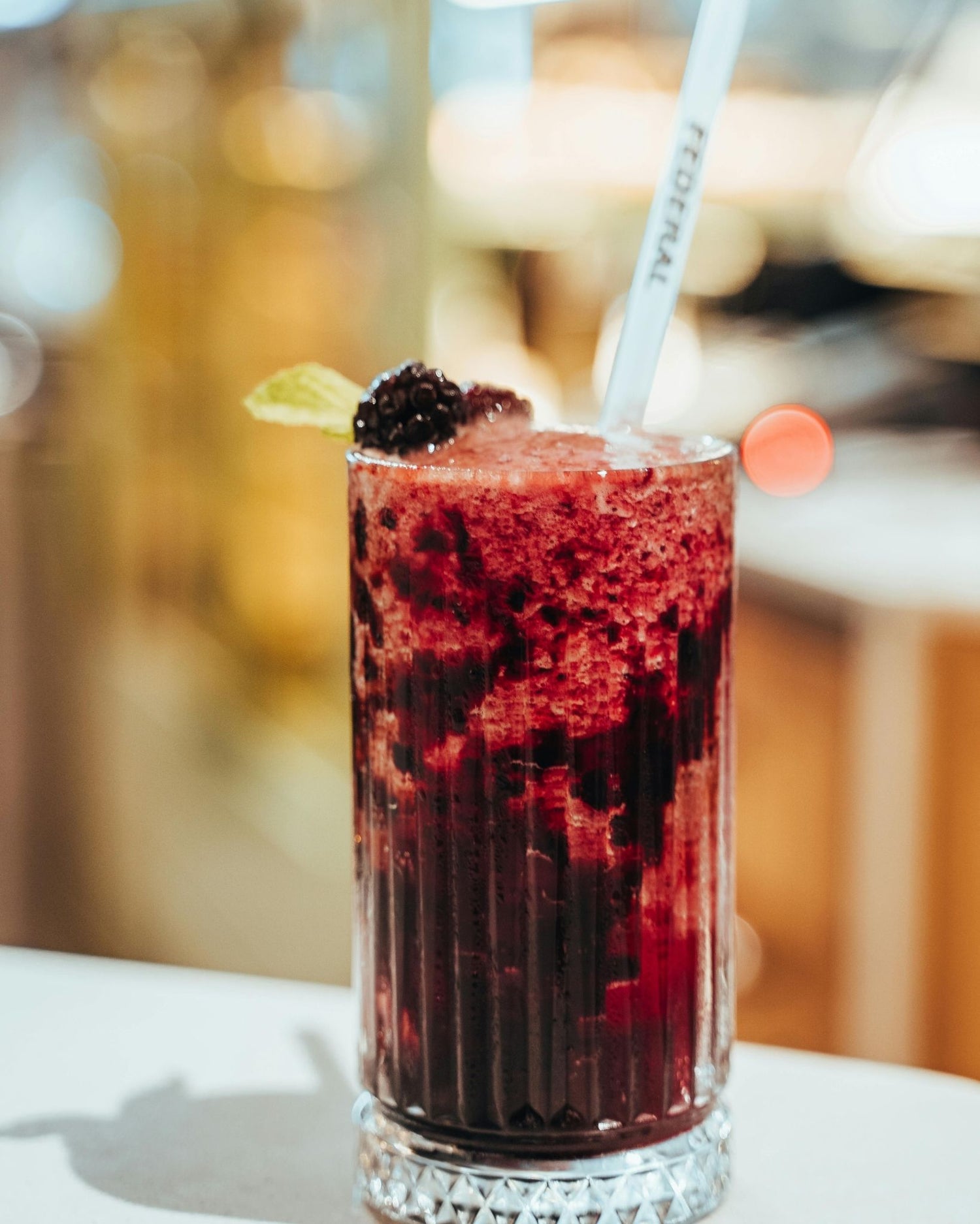 Red Astaxanthin drink with a blackberry and lime wedge in a glass on a blurred background