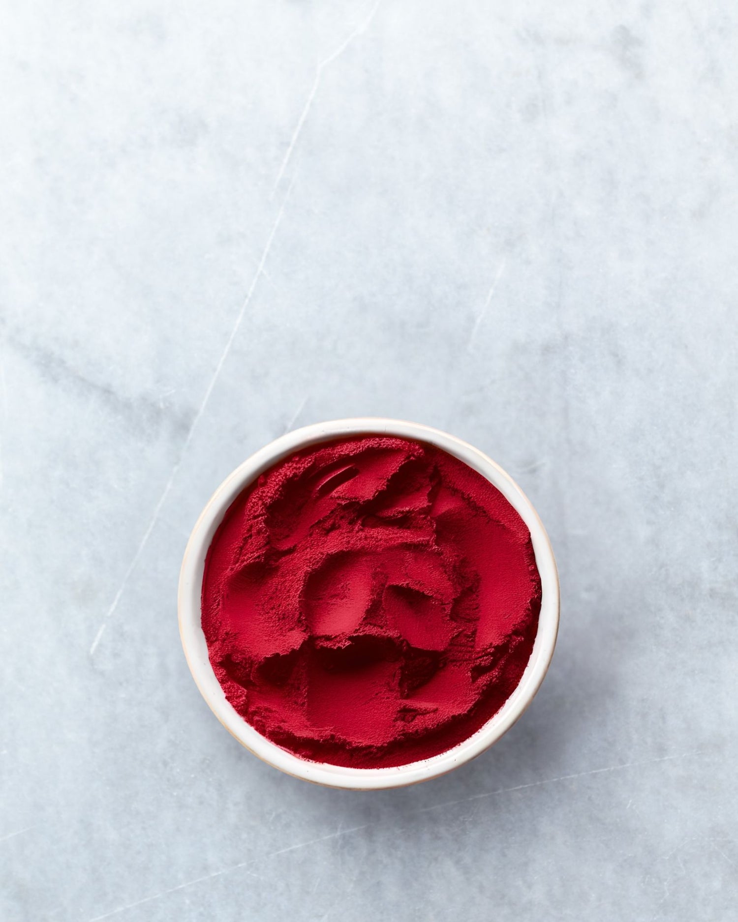 Astaxanthin powder in a white bowl on a light gray background