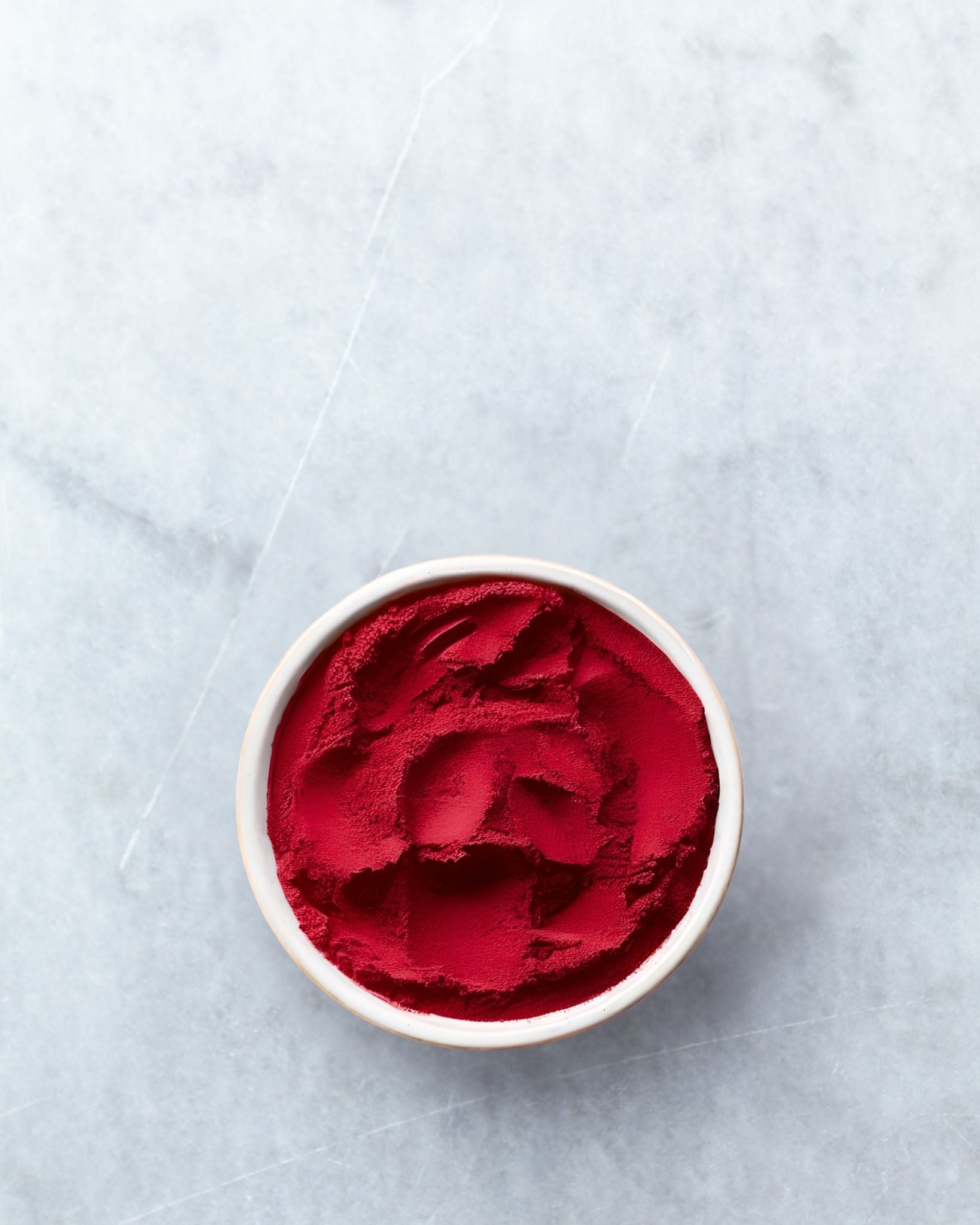 Astaxanthin powder in a white bowl on a light gray background