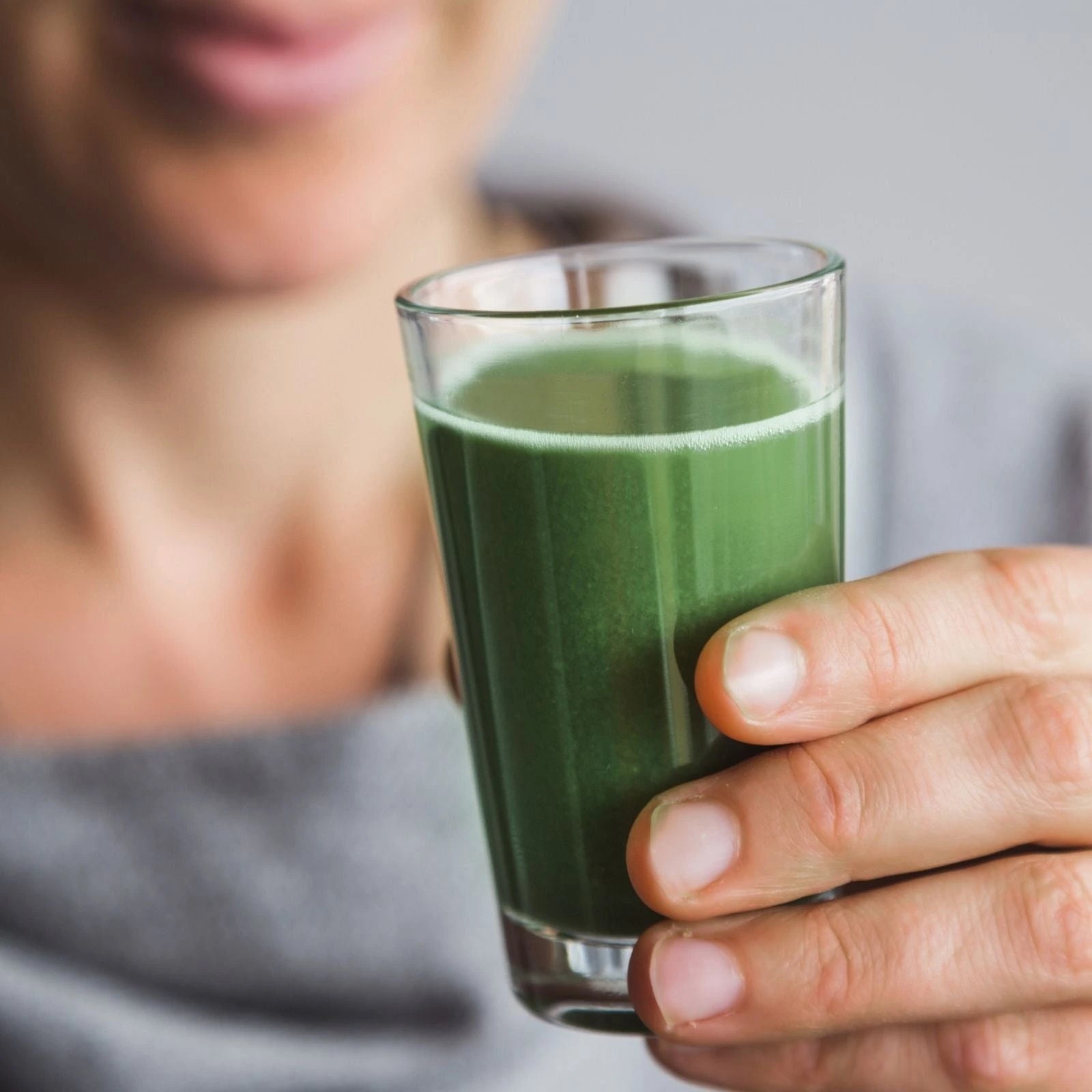 Person holding a glass of green juice