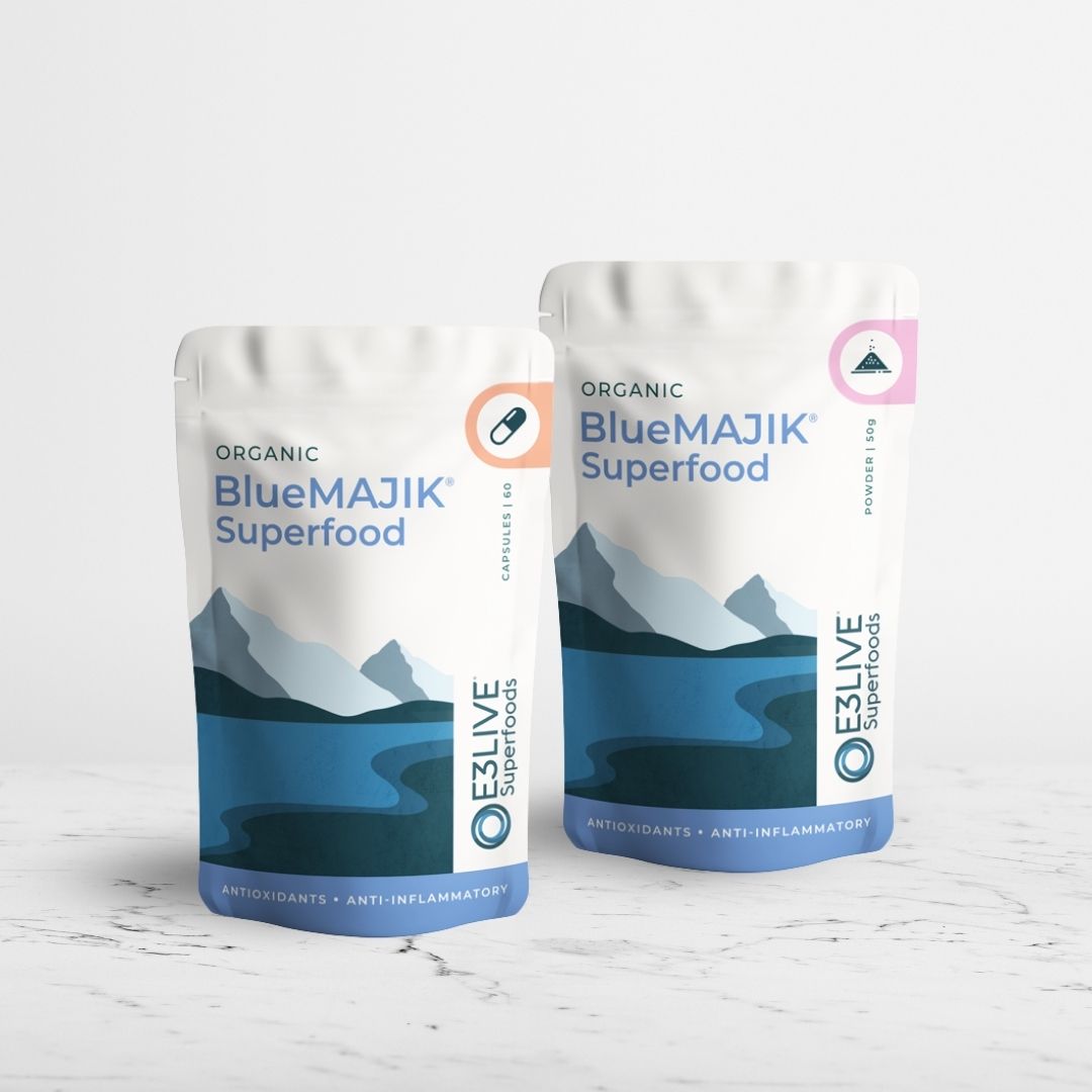 Two packs of Organic BlueMAJIK Superfood - one of capsules and one pack of powder - on a light grey background.