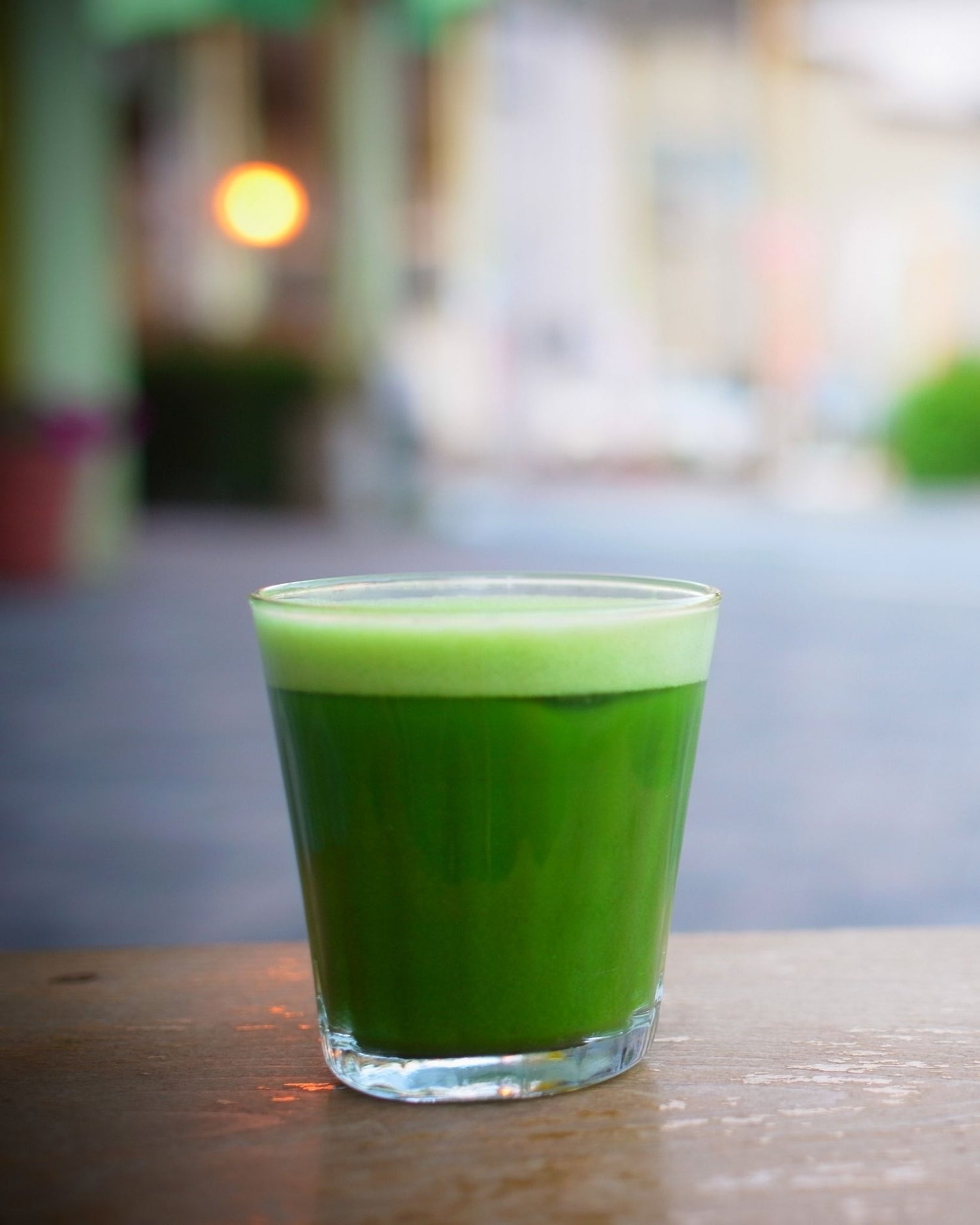 Green juice in a glass on a wooden table with a blurred background