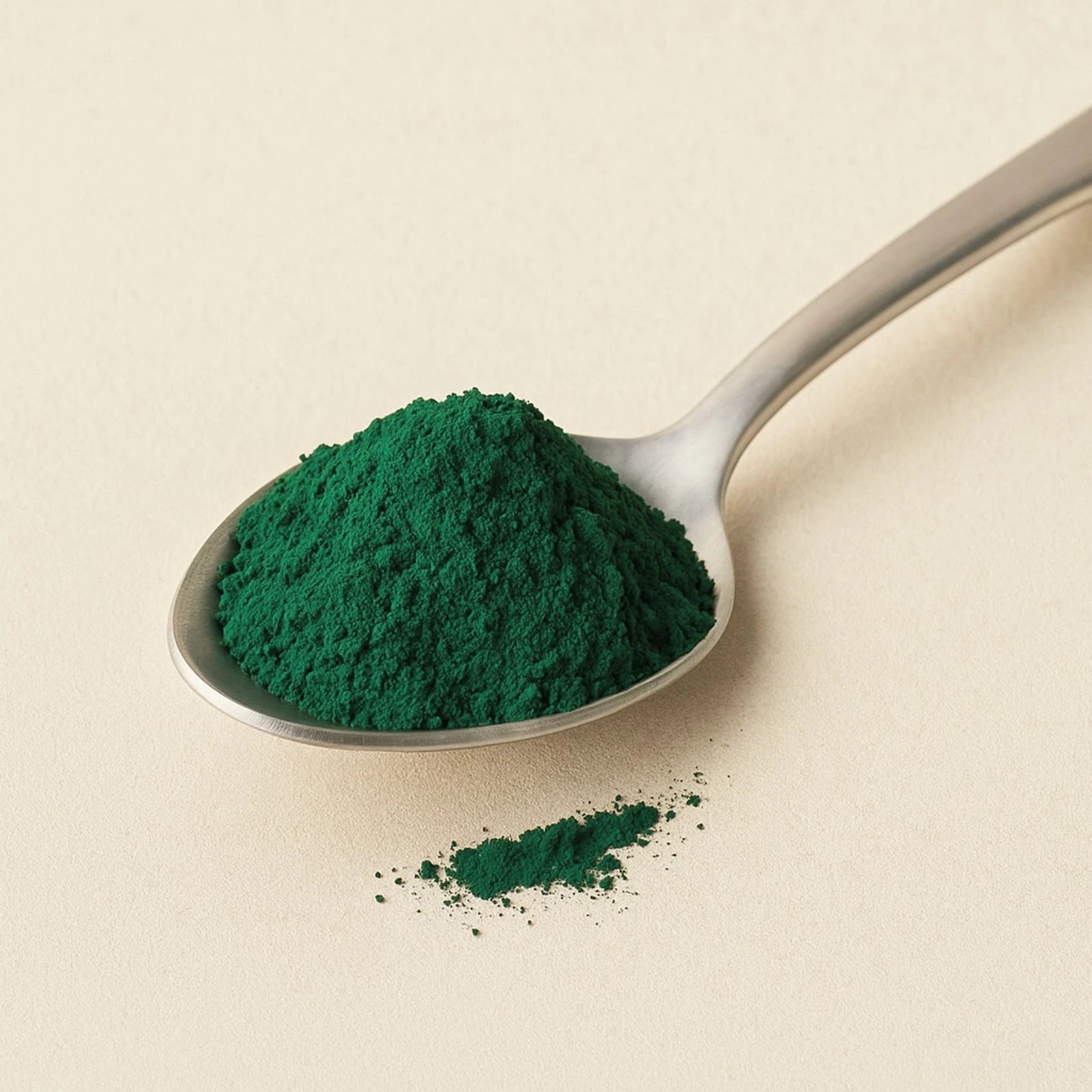 Spoonful of green powder on a beige background