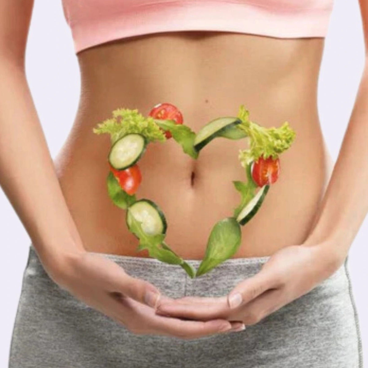 Person holding a heart-shaped arrangement of vegetables over their stomach on a light background
