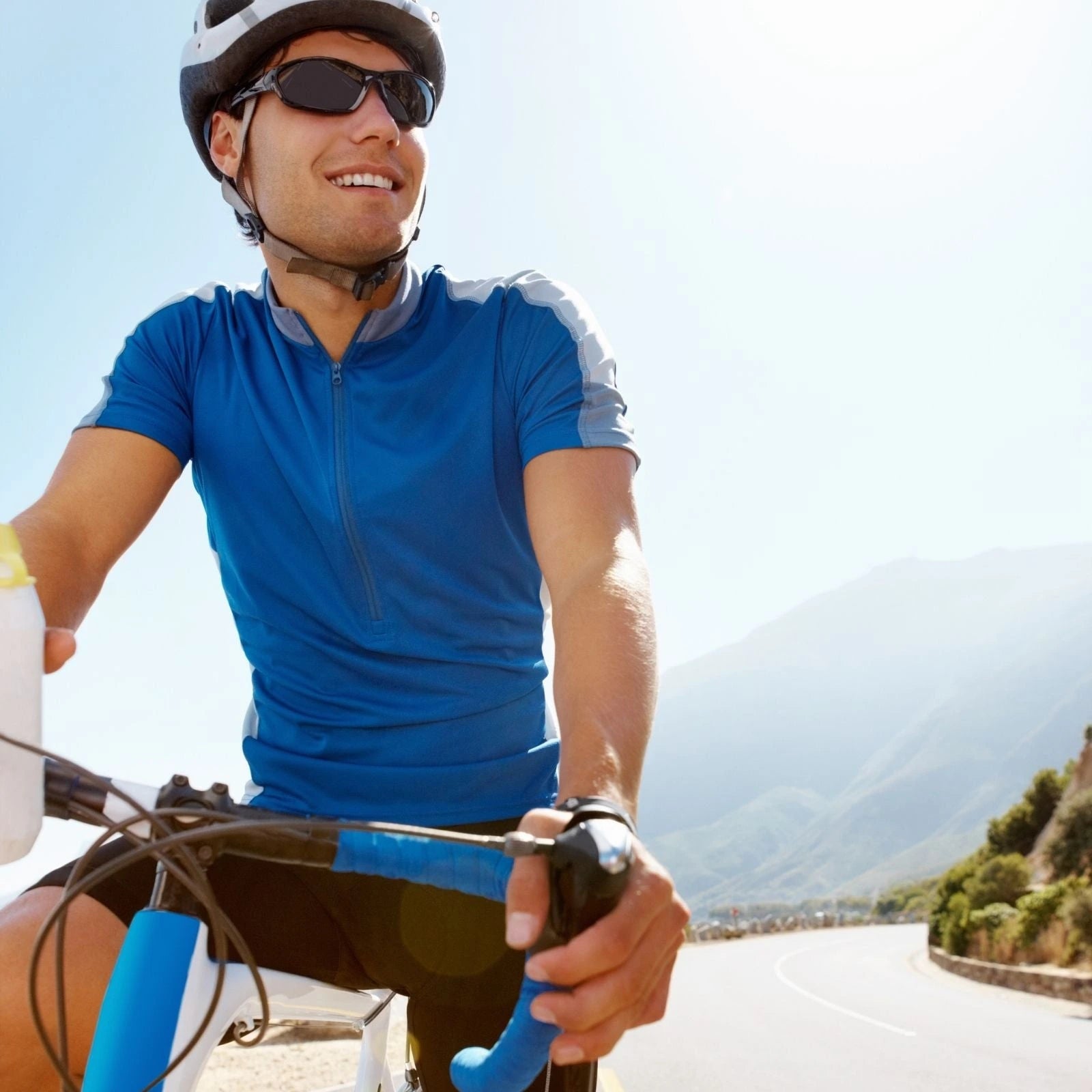 Man riding a bicycle on a sunny day with mountains in the background