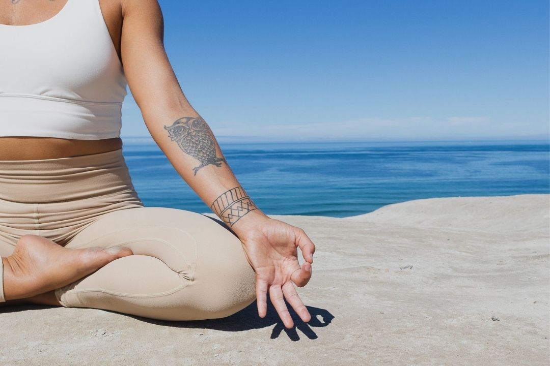 Person meditating on a beach with ocean view