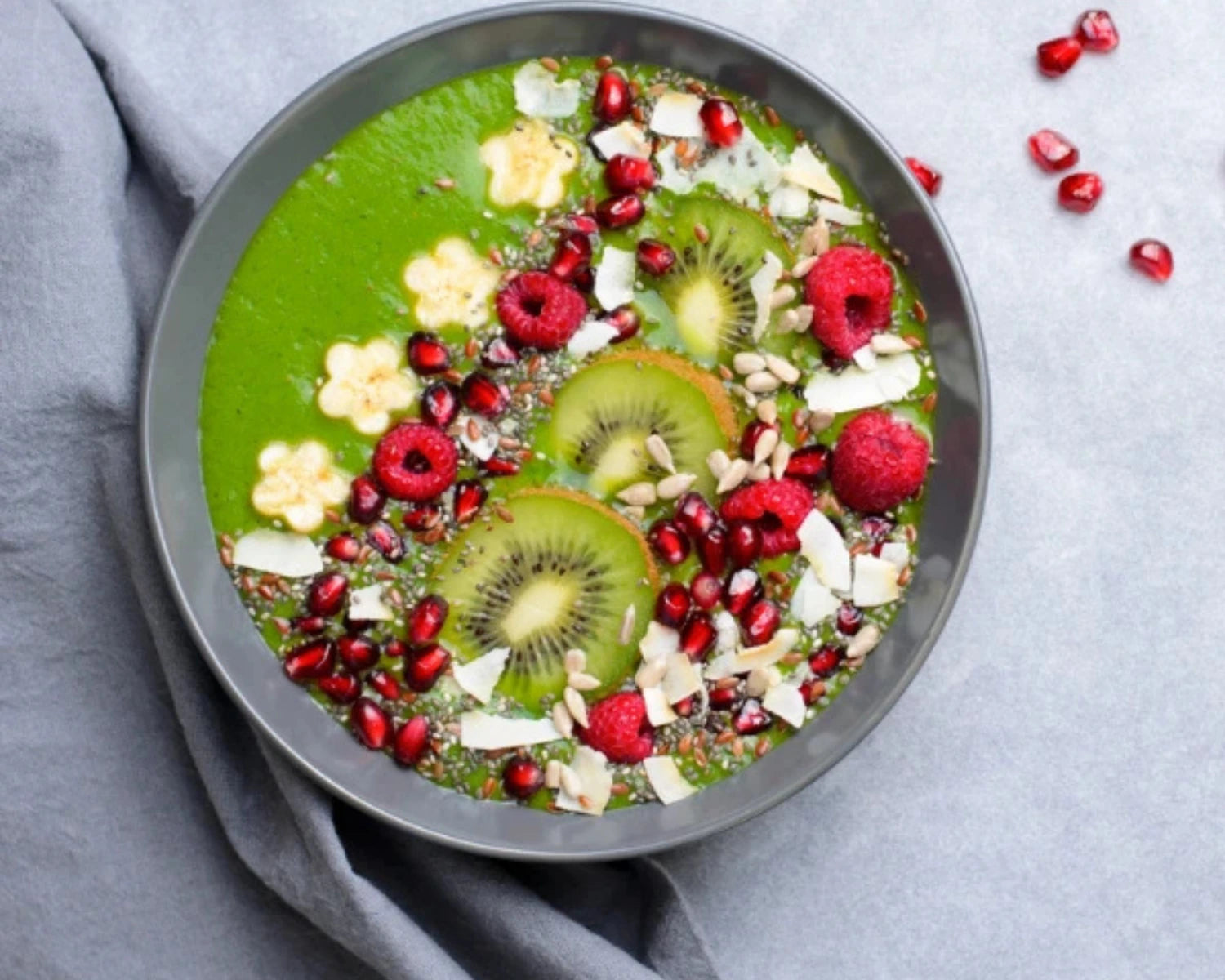 Vitality Smoothie Bowl - Green smoothie bowl with fruits and nuts on a gray surface