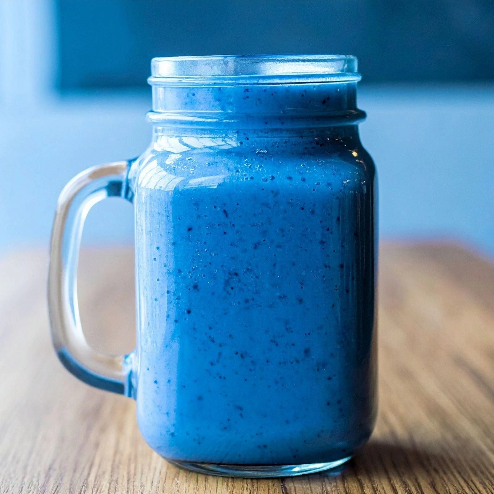 BlueMAJIK smoothie in a mason jar on a wooden surface with a blurred background