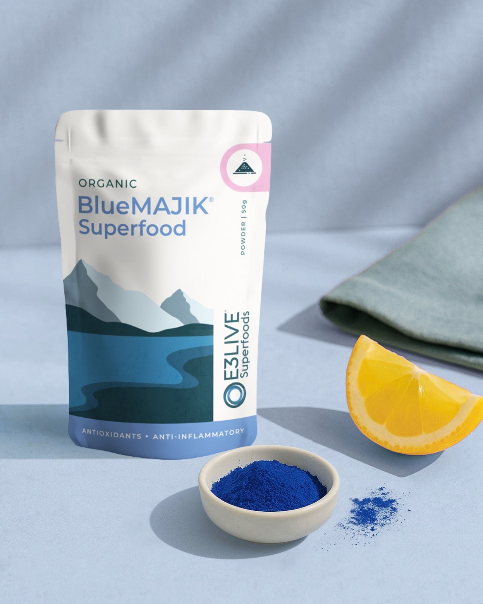 BlueMAJIK Superfood package with a bowl of blue powder and an orange slice on a light gray background