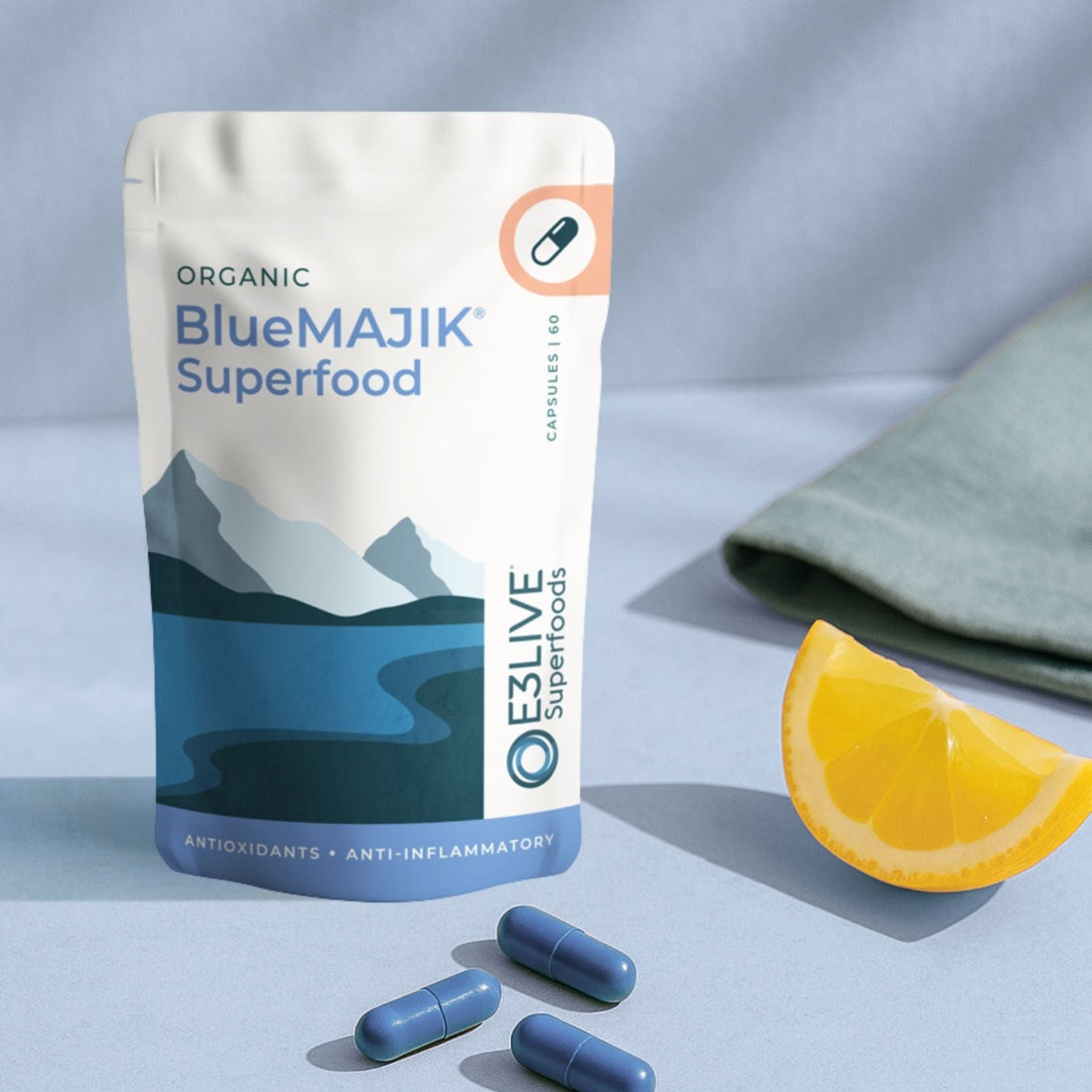 BlueMAJIK Superfood package with capsules and an orange wedge on a light blue background
