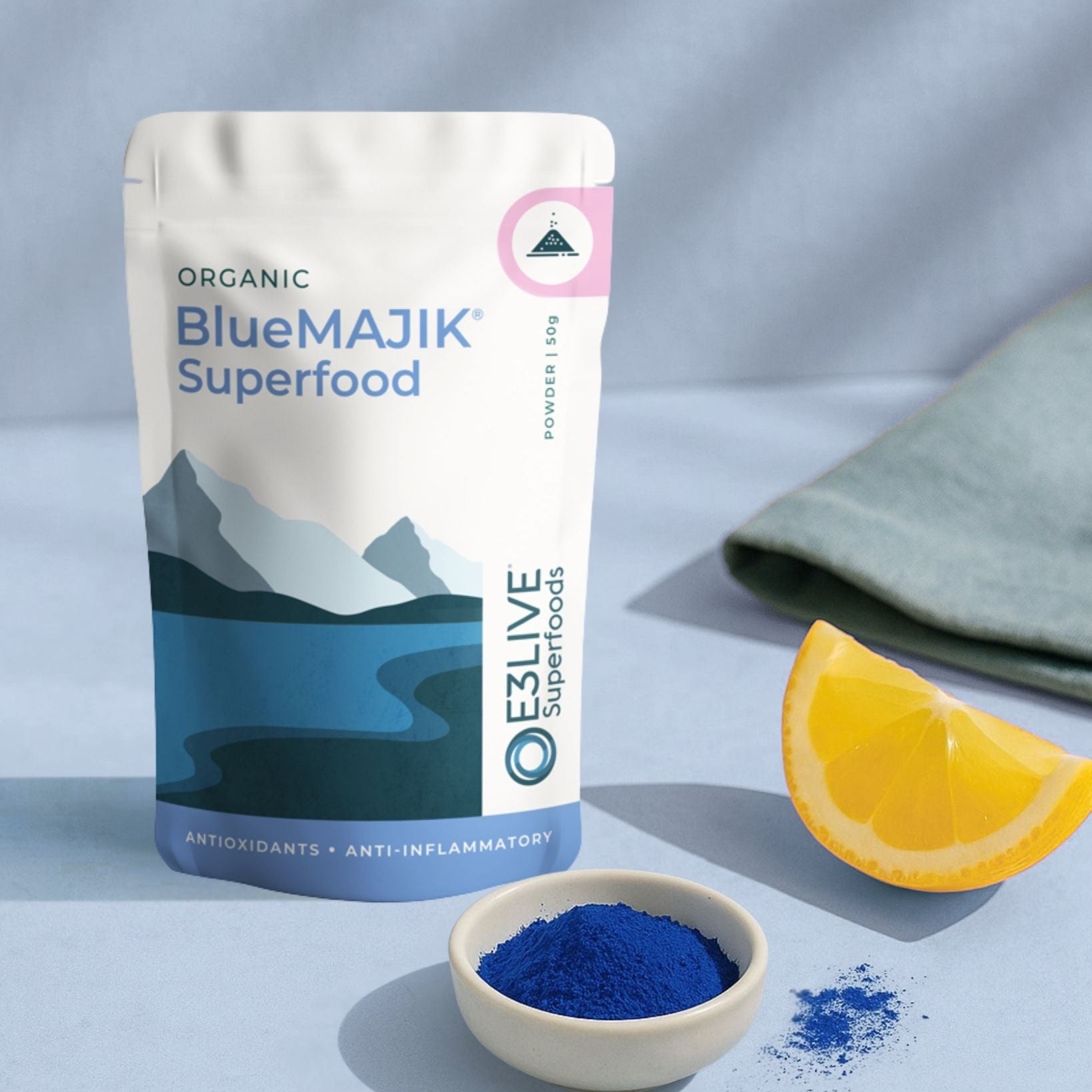 BlueMAJIK Superfood package with a bowl of blue powder and an orange slice on a light gray background