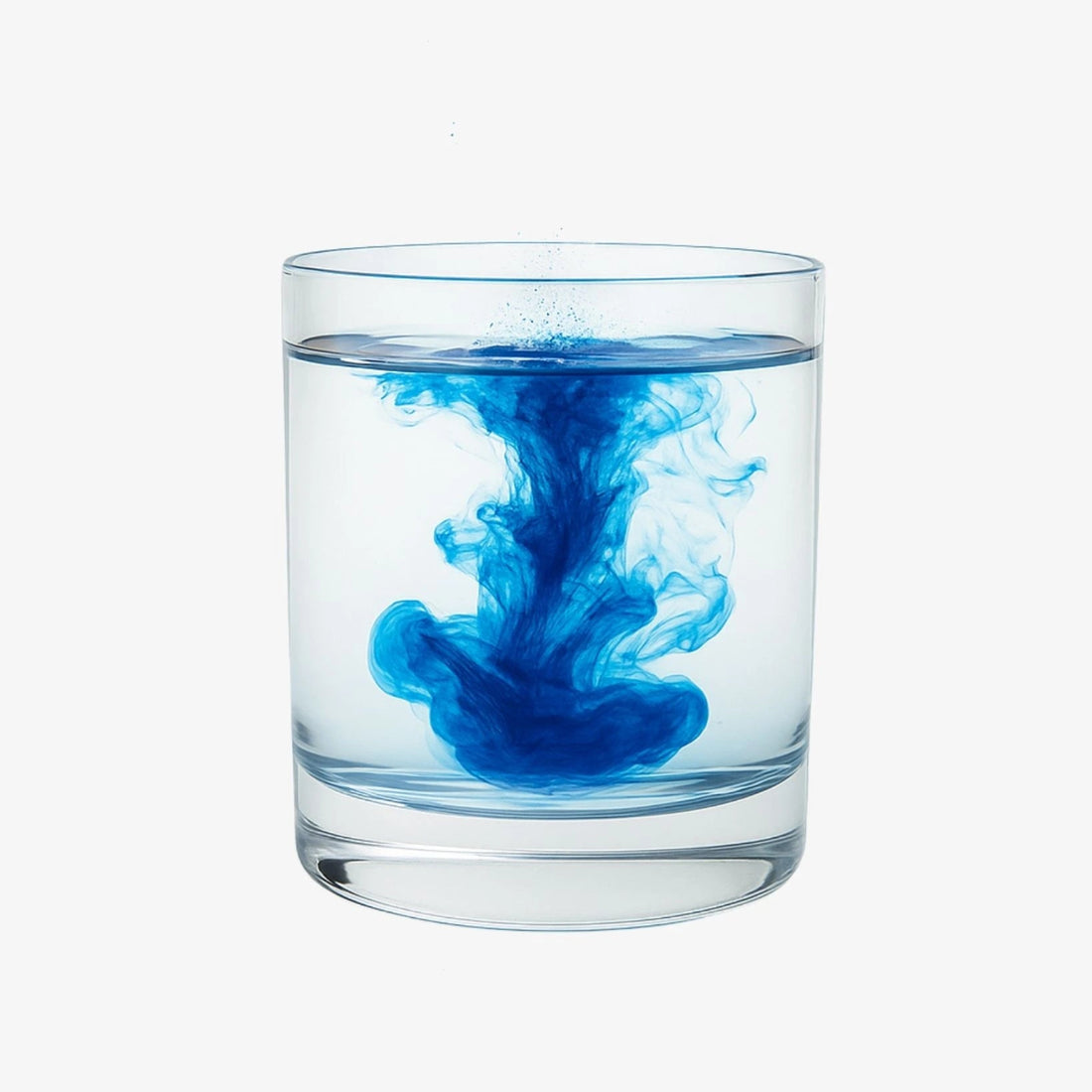 Glass of water with blue ink swirling inside on a white background