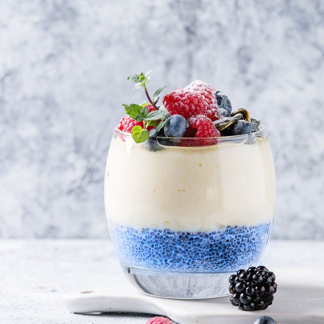Blue Chia Seed Pudding made with BlueMAJIK®, topped with cashew cream, fresh berries, and a sprig of mint.