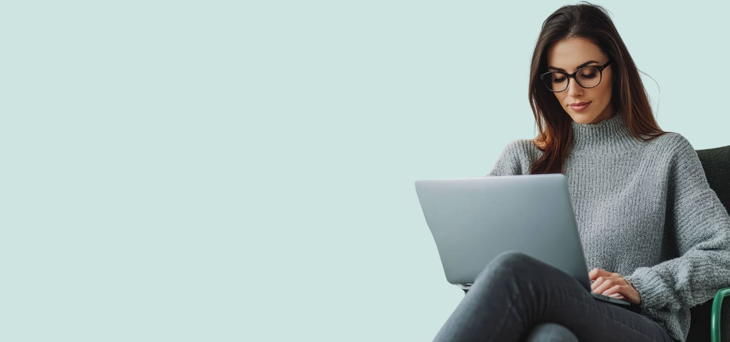 Woman using a laptop on a light teal background