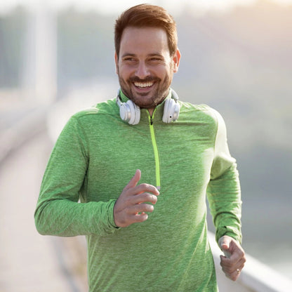 Man in green athletic jacket with white headphones jogging outdoors