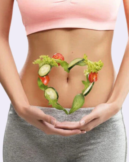 Person holding a heart-shaped arrangement of vegetables over their stomach on a light background