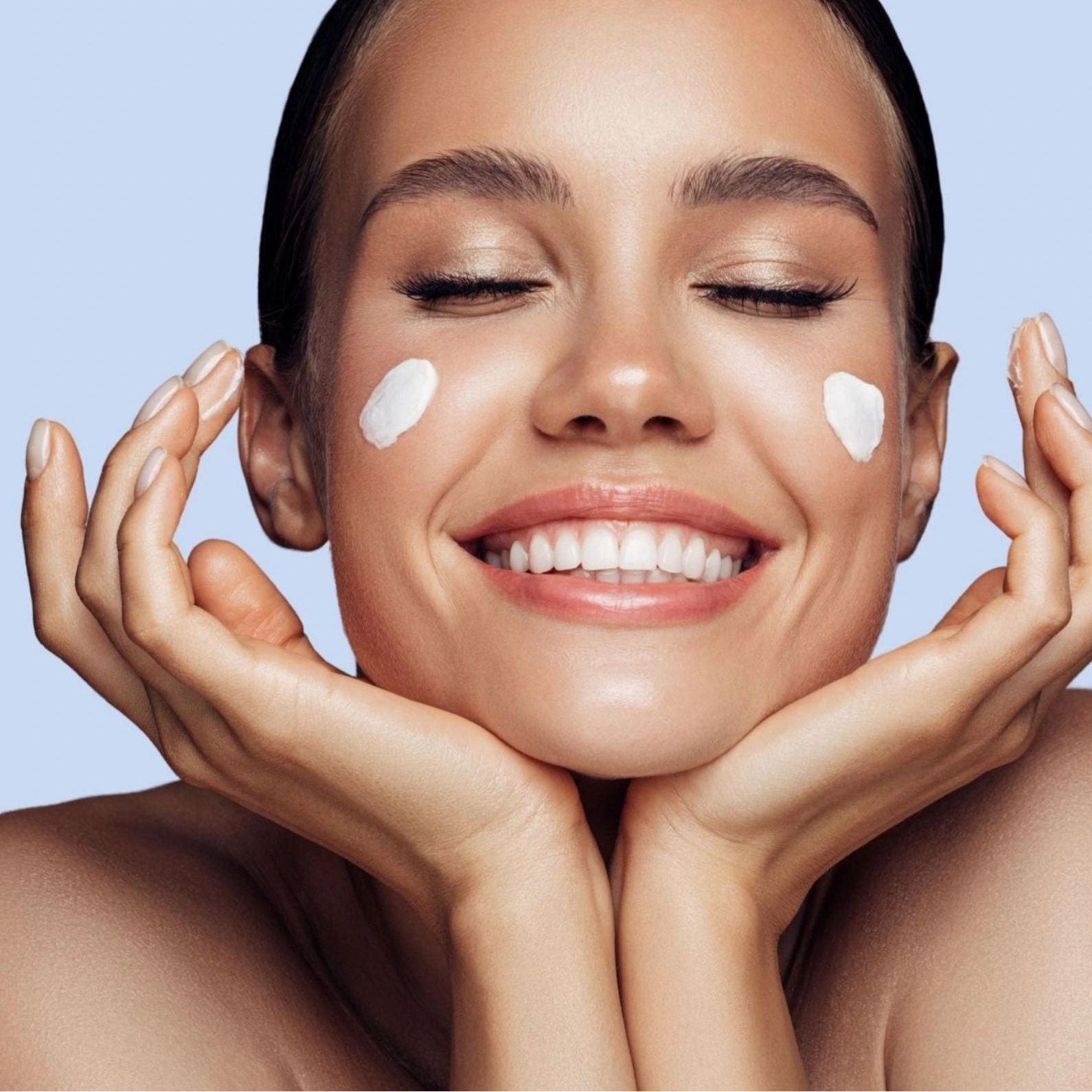 Woman applying cream to her face with a blue background