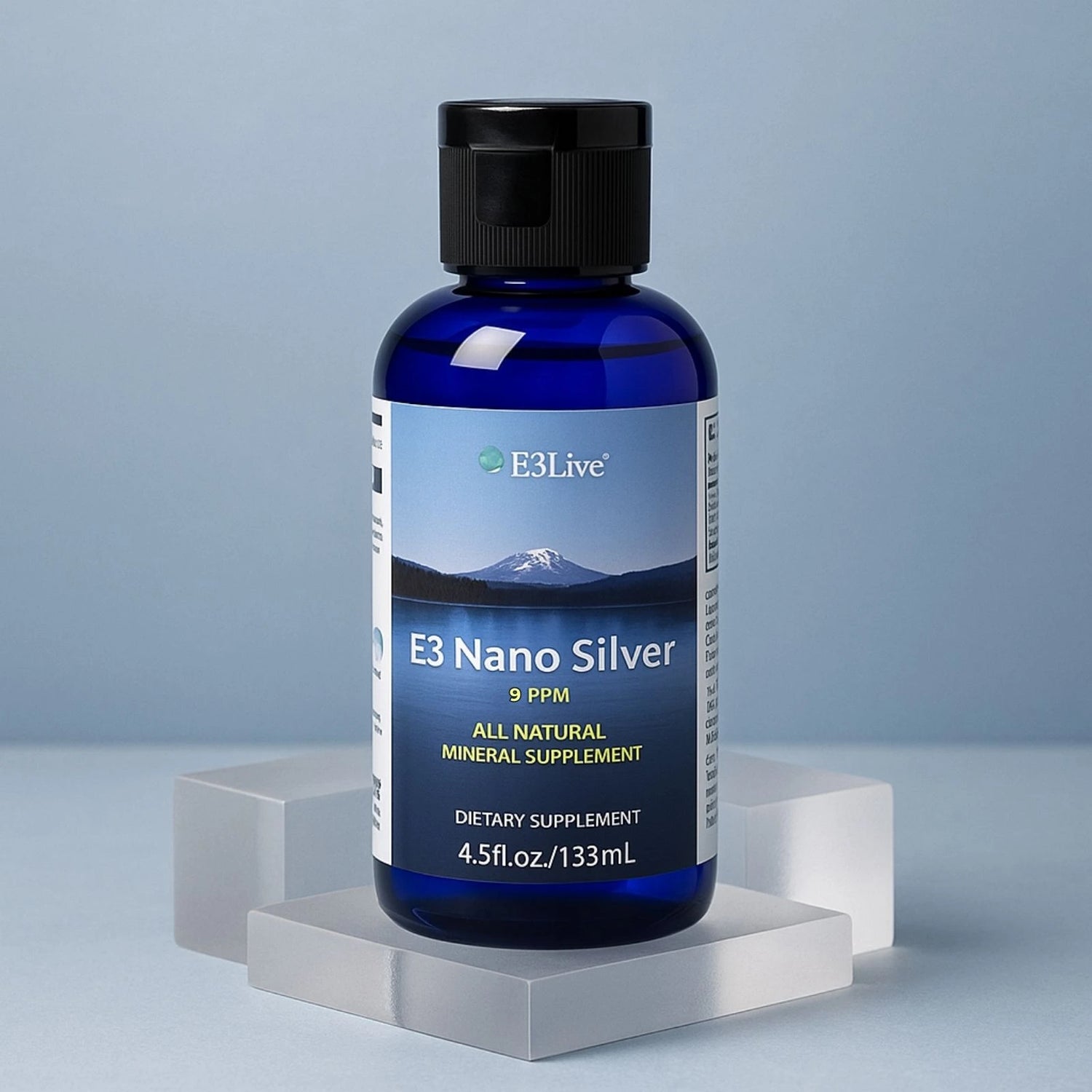 E3 Nano Silver dietary supplement bottle on a gray platform with a light blue background