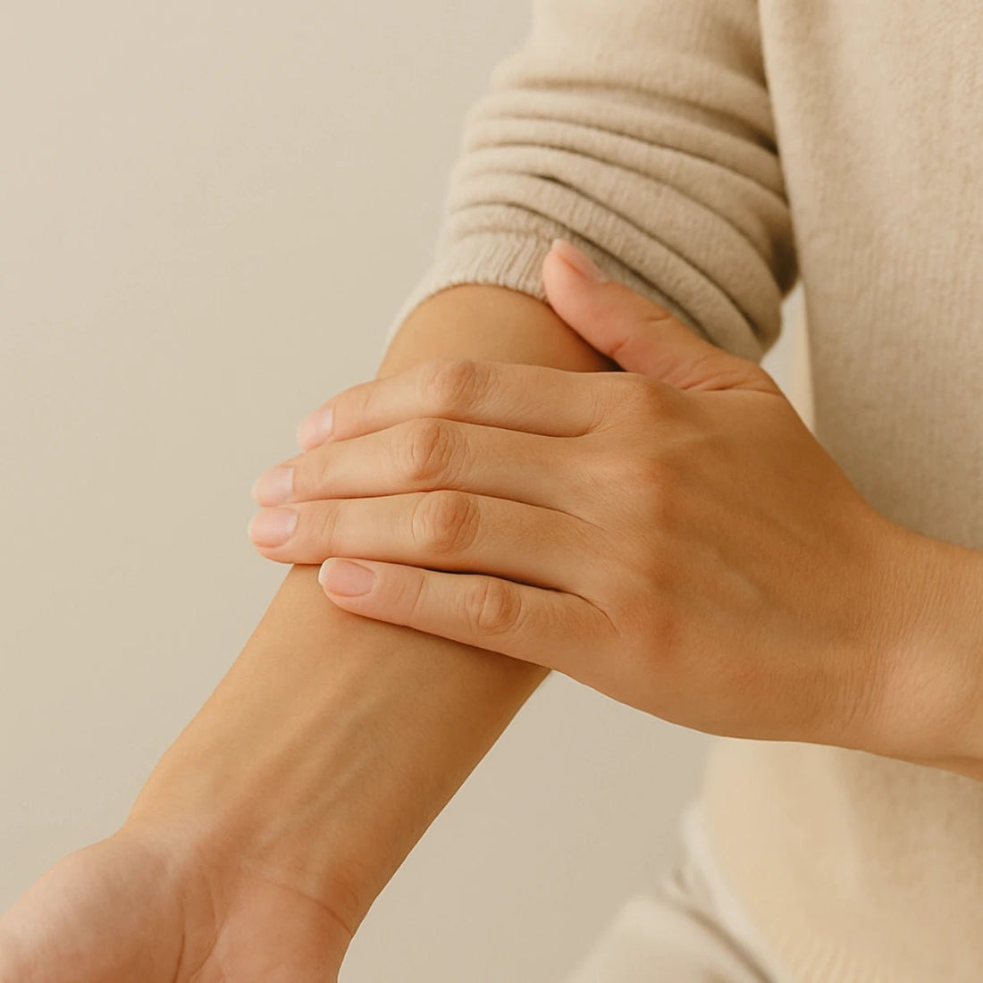Person wearing a beige sweater holding their arm against a neutral background representing Inflammation & Joint Health.