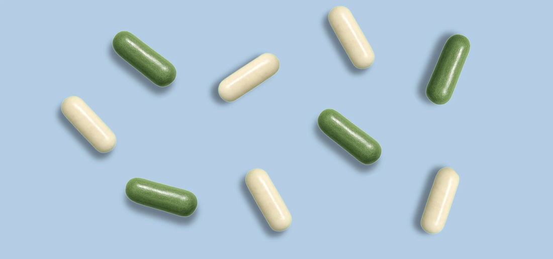 Green and off-white capsules scattered on a light blue background