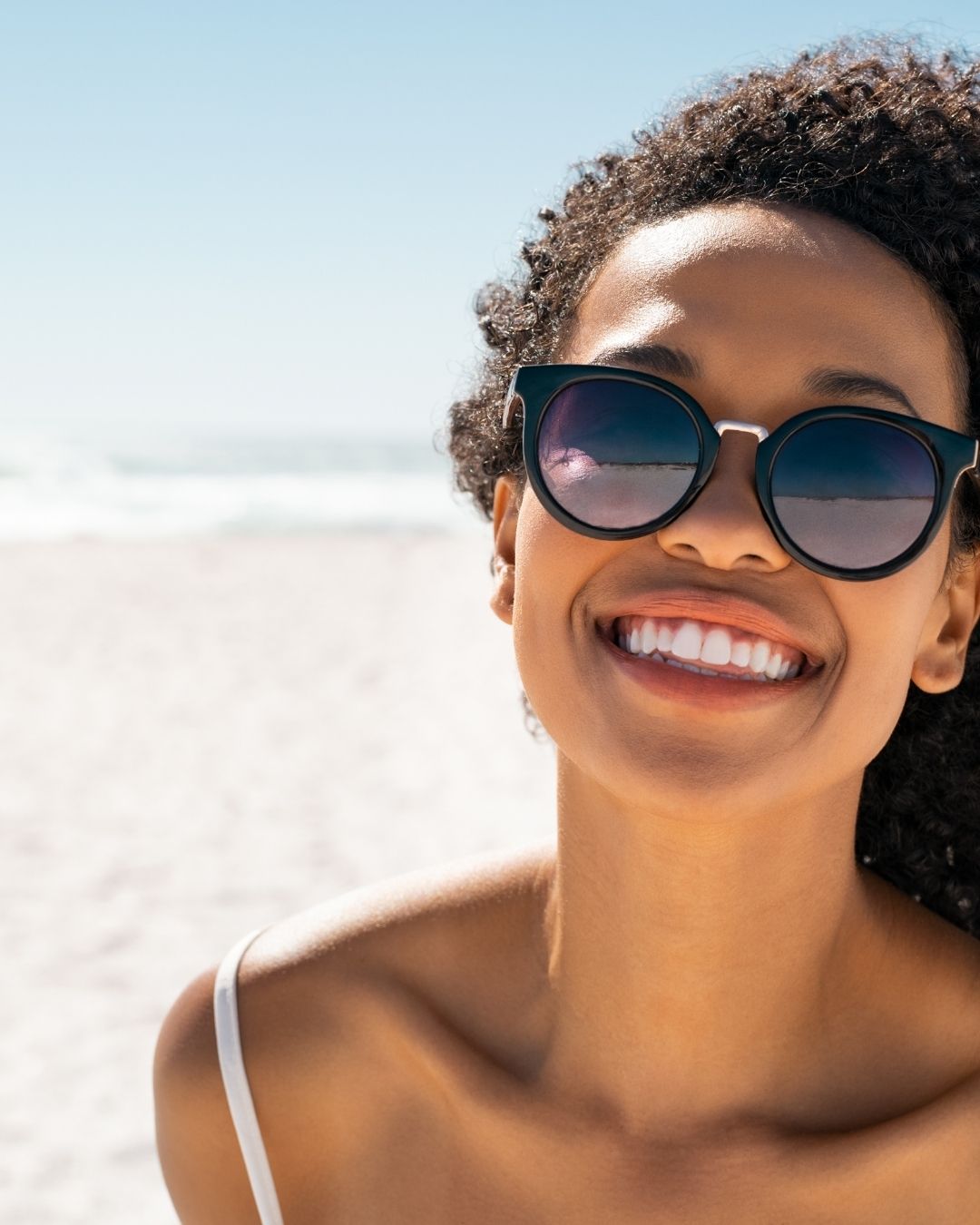 Woman wearing sunglasses with a beach background