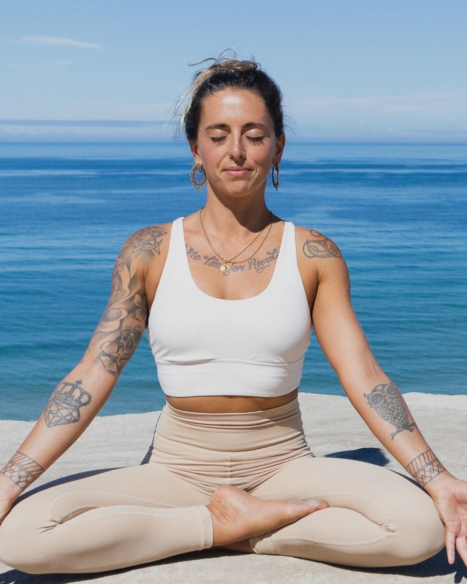 Woman meditating on a beach with ocean in the background