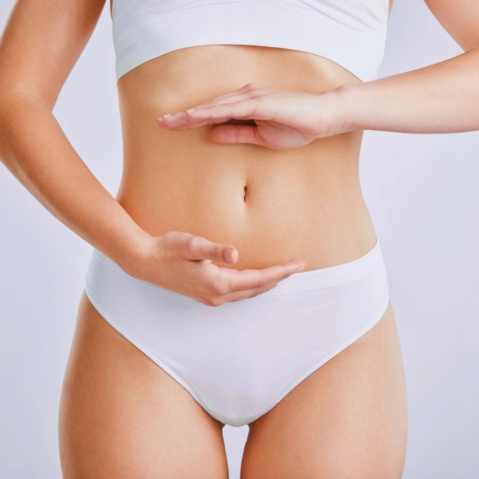 Woman in activewear holds her abdomen, showing the digestive balance and wellness from E3Live Superfoods.
