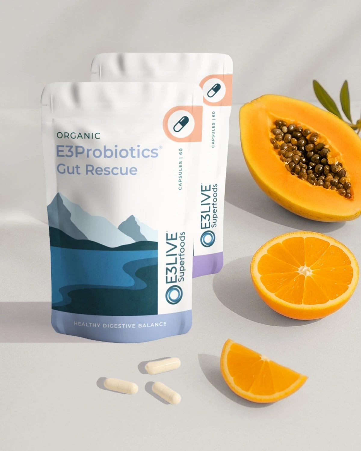 E3Probiotics Gut Rescue package with E3Enzymes behind it with papaya and orange on a light gray background