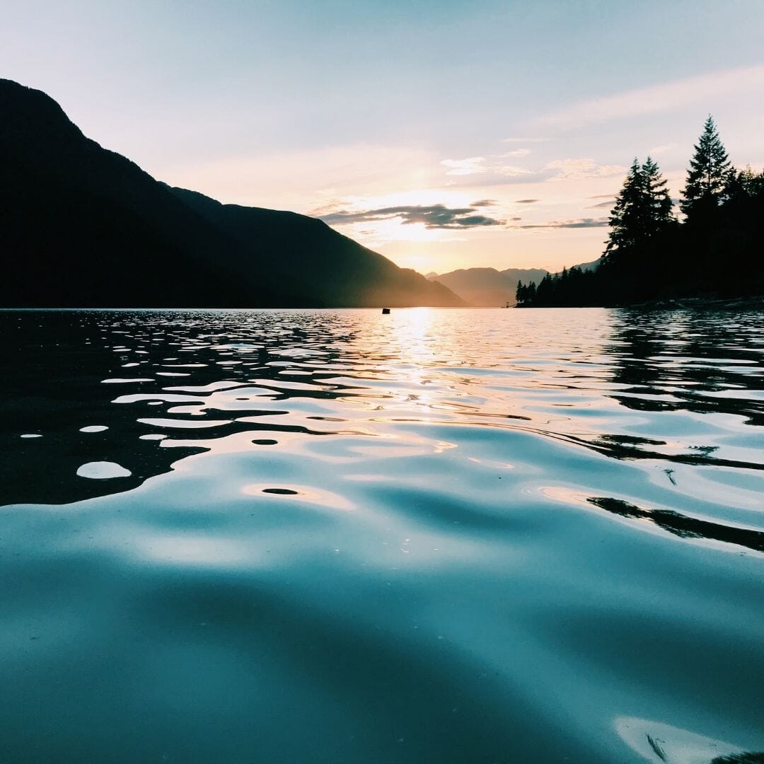 Sunset over a lake with mountains and trees in the background